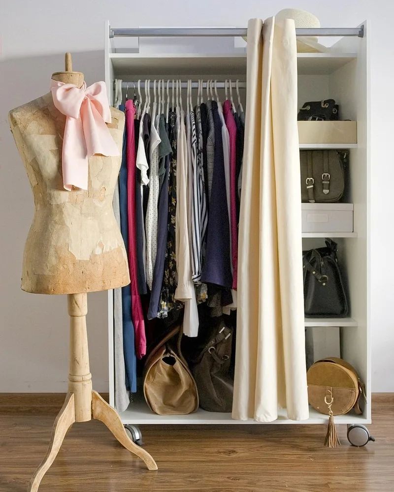 A rail of neutral clothing in a bright room.
