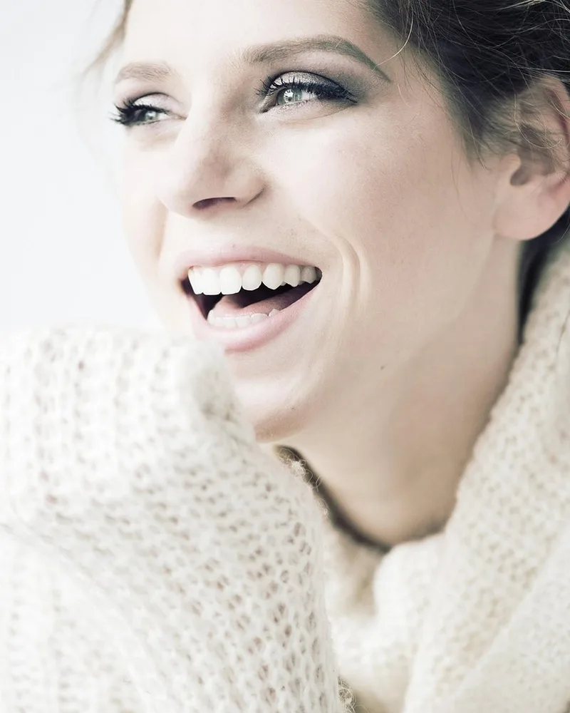 A chunky cream knit sweater folded on a wooden surface.