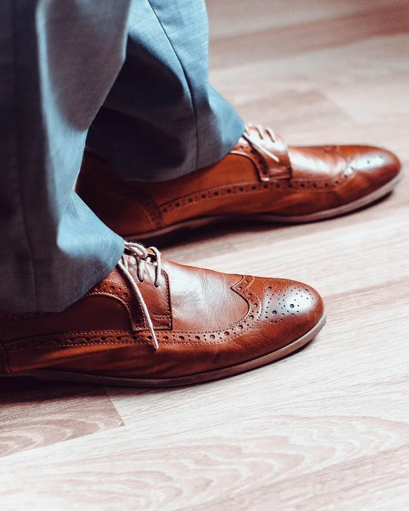 A pair of brown leather brogues on a pale floor.