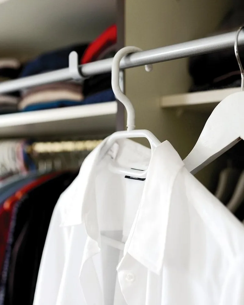 A wardrobe rail with hanging shirts.