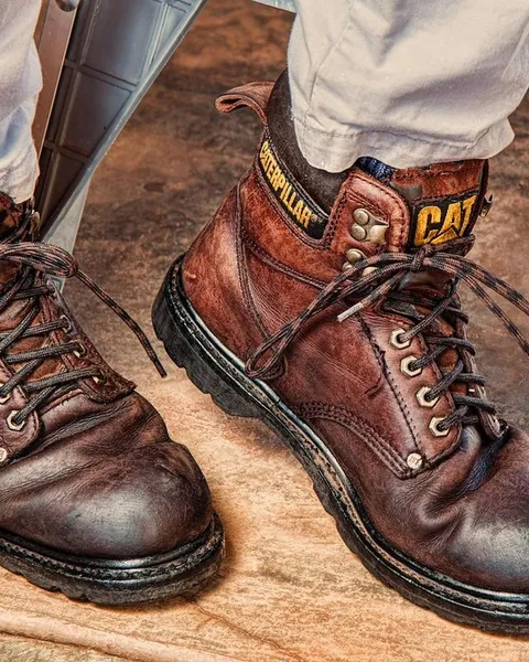 Brown leather boots worn with cuffed jeans.