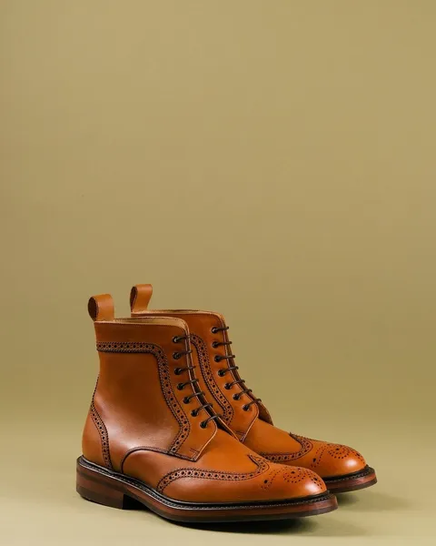 A pair of tan leather boots on a plain backdrop.