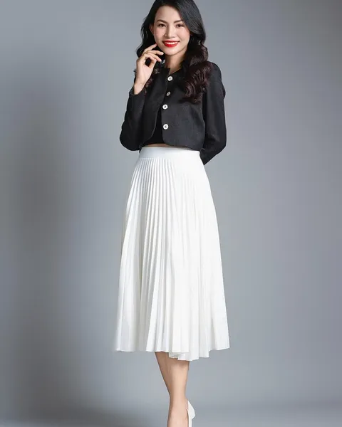 A woman in a black shirt and white pleated skirt.