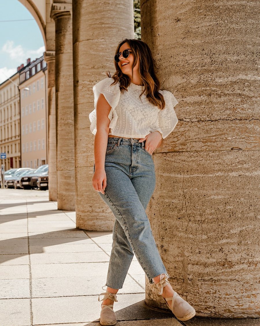 A blazer over a plain tee with straight trousers, photographed against a plain wall.