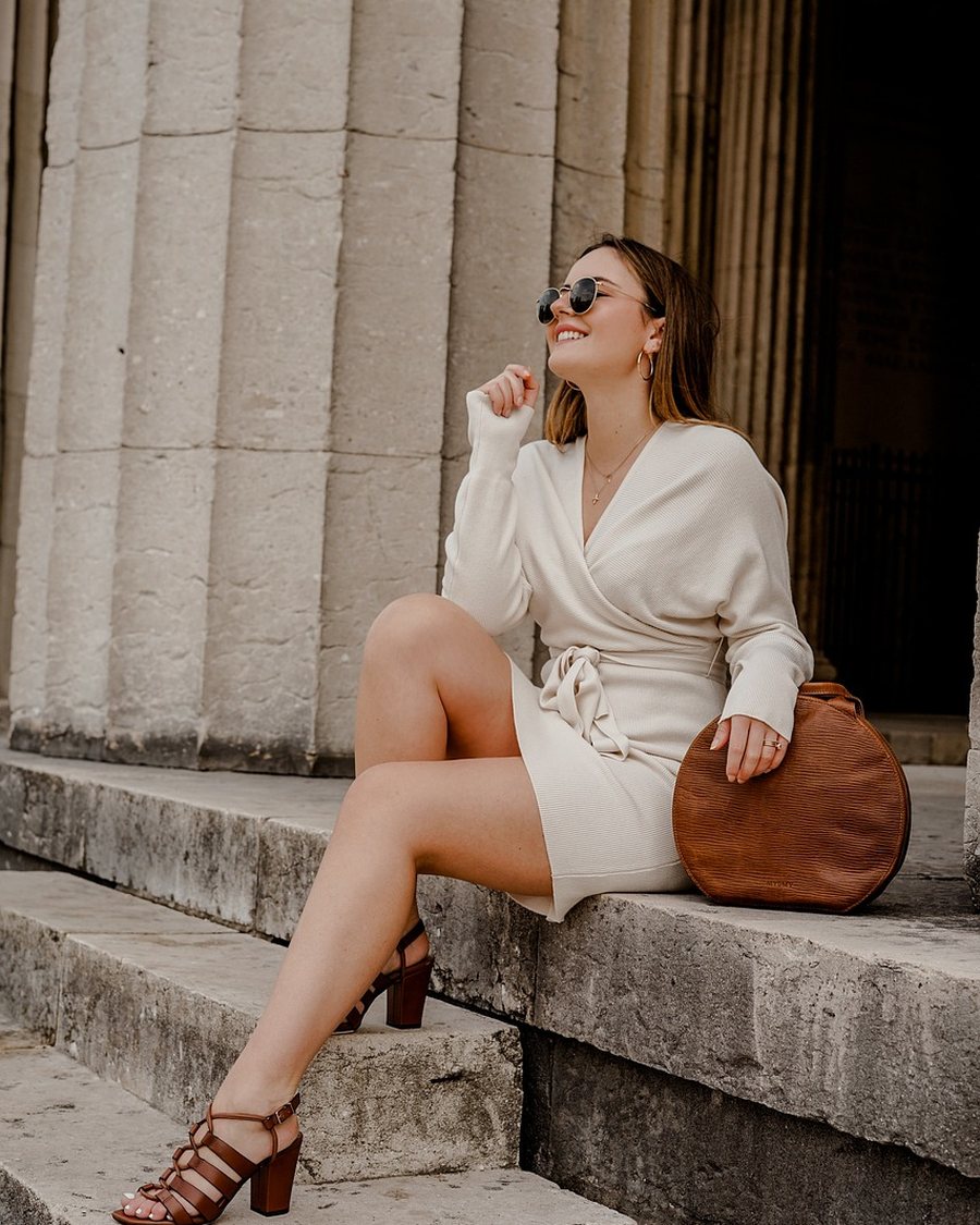 A woman in a white suit sitting on stone steps.