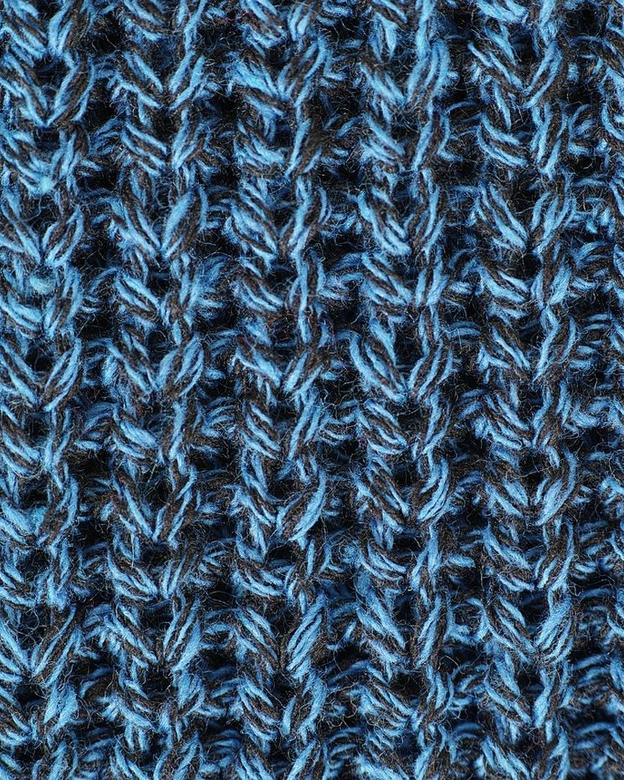 A macro photograph of blue knit stitches.