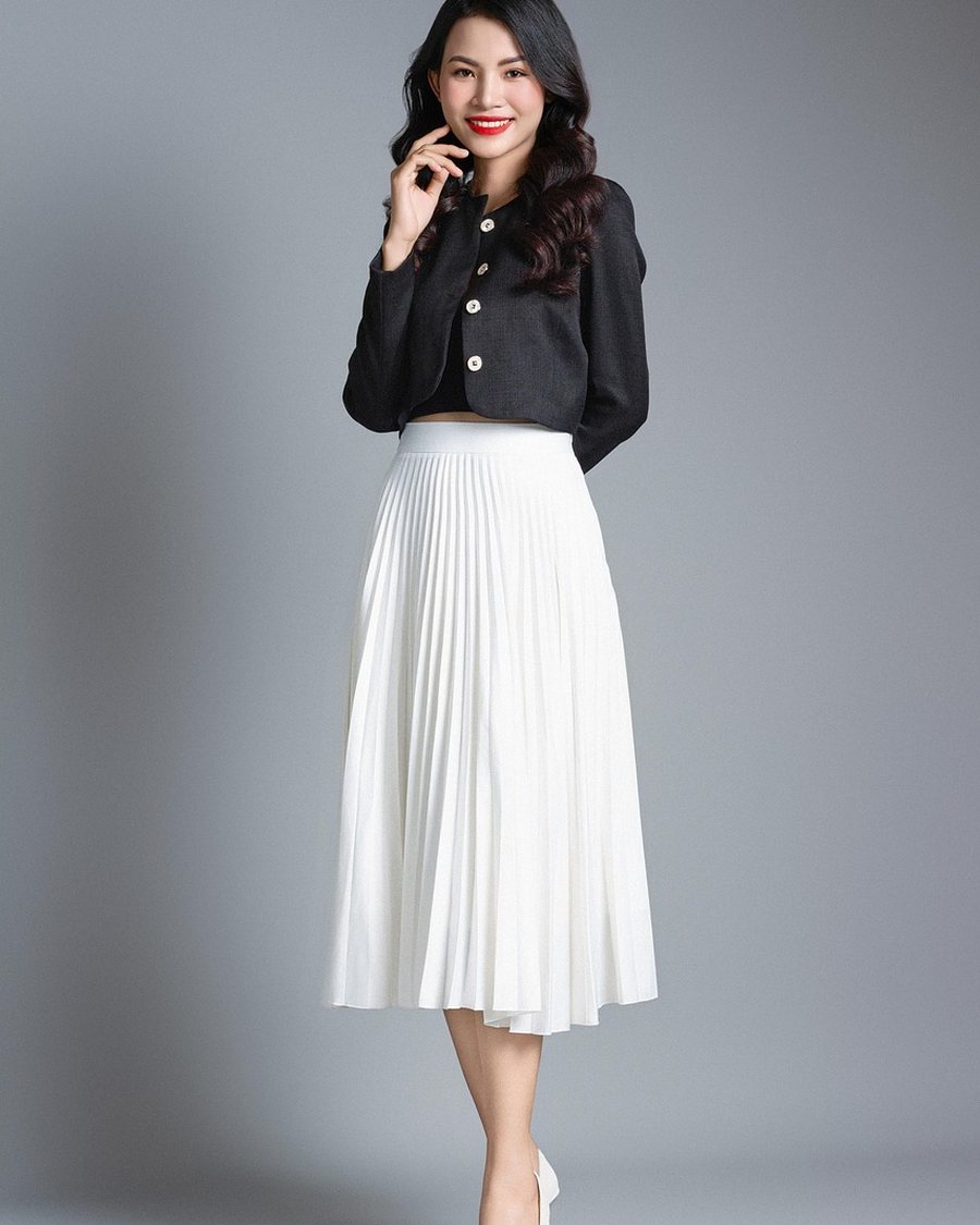 A woman in a black shirt and white pleated skirt.
