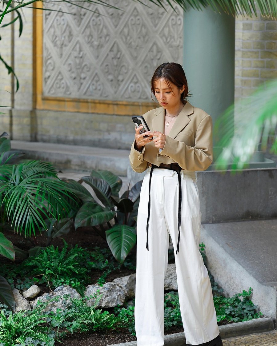 A woman in wide ivory trousers standing on stone paving.